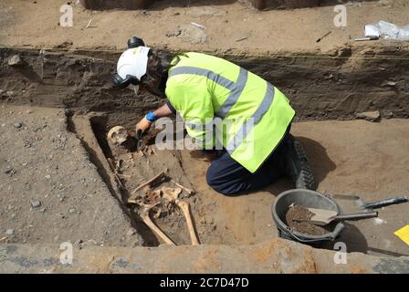 Ein Archäologe von der Straßenbahn nach Newhaven Projekt Ausgraben von menschlichen Überresten, die bis 1300 zurückreichen könnte, aus den Gräbern der South Leith Pfarrkirche, deren mittelalterlicher Friedhof erstreckt sich unter der Straßenoberfläche der Constitution Street, Leith. Stockfoto