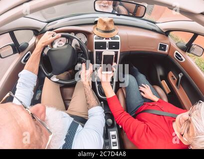 Glückliches älteres Paar mit Spaß an dem neuen Cabrio-Auto - Reife Menschen genießen zusammen Zeit während des Urlaubs auf der Straße Stockfoto