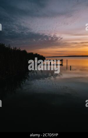 Silhouette von Pflanzen und ein Pfad über dem Wasser unter Ein wolkig Himmel in einer vertikalen Aufnahme Stockfoto