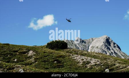 Hubschrauber fliegen über die felsigen Berge bei einem sonnigen Sonnenuntergang. Luftlandschaft aus österreichischen Alpen.Panorama Natur Hintergrund Stockfoto