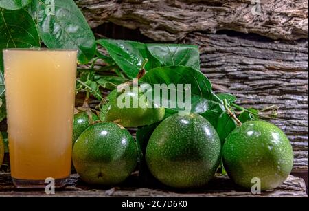 Frischer und gefrorener Passionsfruchtsaft. Grüne Früchte. Blätter auf Holzgrund. Gesundes Getränk. Tropischer Fruchtcocktail. Erfrischendes Getränk. Natürliches dri Stockfoto