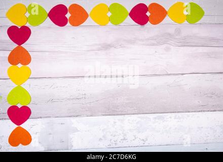 Bunte Filz Herzen auf dem Hintergrund der alten hölzernen Planken ähnelt einem alten Parkettboden. Konzept der Valentinstag und die Liebe im Allgemeinen. Stockfoto