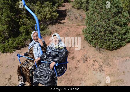 Zwei asiatische ältere Frauen fahren mit einer Seilbahn in den Bergen. Berge von Usbekistan, Beldersay. Stockfoto