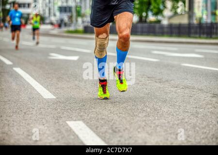 Beine Läufer Mann in Kompressionssocken und Knieschoner Rennen die Straße hinunter Stockfoto
