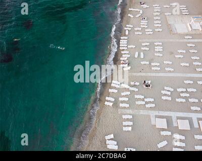 Strand und Sonnenliegen am Meer mit smaragdgrünem Wasser. Sommerurlaub am Meer. Stockfoto