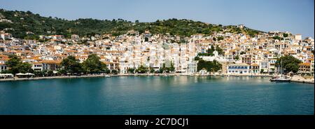 Panoramablick auf die historische Stadt auf der Insel Skopelos vom Boot aus gesehen, wenn man im Sommerlicht in den Hafen einfährt. Stockfoto