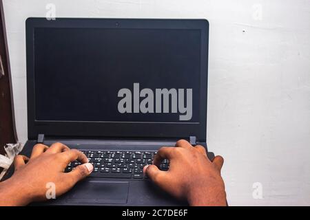 Arbeit von zu Hause - man's Hände mit Laptop mit Bildschirm auf dem Schreibtisch in der Wohnung. Mockup-Stil Bild einer Hand mit und berühren Laptop auf dem Tisch bei hom Stockfoto
