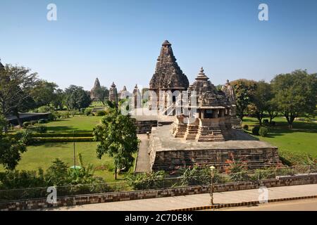 Horizontale Aufnahme von Khajuraho Tempel in Indien umgeben von schönen Grüne Bäume und Blumen Stockfoto