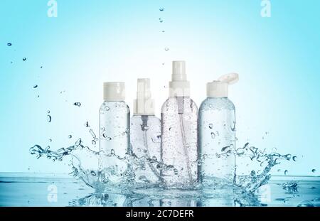 Flaschen von Beauty-Produkten in einem Wasserspritzer isoliert auf blauem Hintergrund Stockfoto