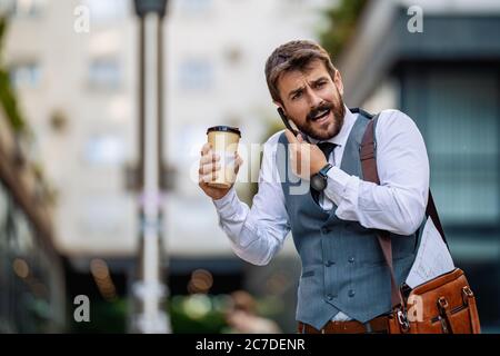 Attraktiver junger Geschäftsmann, der ein Smartphone verwendet.Porträt eines gutaussehenden Geschäftsmannes im Freien in der Stadt. Stockfoto