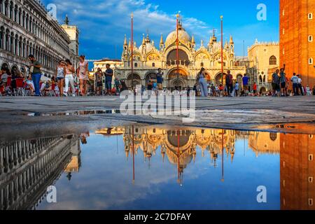 Basilica San Marco spiegelt sich in Acqua alta auf dem Piazza San Marco in der Dämmerung während Sonnenuntergang, Venedig, Italien mit Bewegung verschwimmen auf die Massen von Touristen Stockfoto