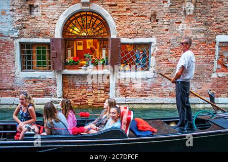 Mann mit Gondel fährt an einem Kanal in Venedig vorbei an einem Restaurant im Freien. Outdoor Ristorante in Fondamenta de l'Osmarin, San Marco, Venedig, Italien A Stockfoto