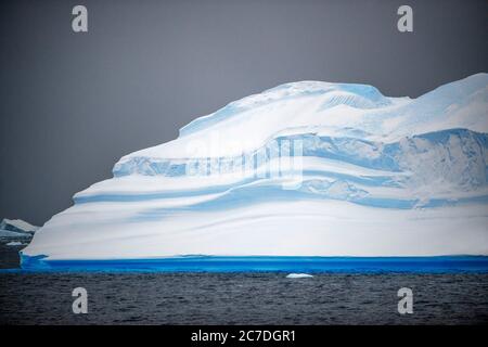 Großer Eisberg und launischer Himmel Portal Point Antarktische Halbinsel Antarktis. Der RCGS Resolute One Ocean Navigator, ein 5-Sterne-polarer, eisverstärkter exped Stockfoto