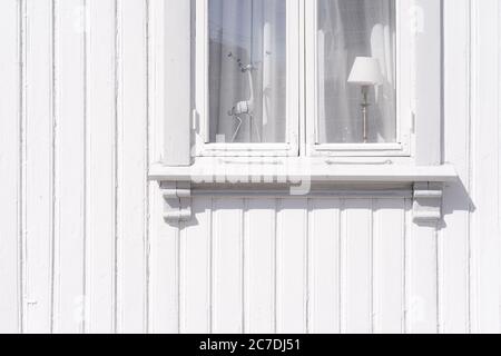 Nahaufnahme einer weißen Holzhauswand mit einem Weißer Fensterrahmen und Hirschskulptur sichtbar Stockfoto