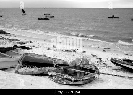 Verwitterte Daus am Sandstrand in einem kleinen Fischerhafen in Maputo, Mosambik, am frühen Morgen, in Schwarzweiß fotografiert Stockfoto