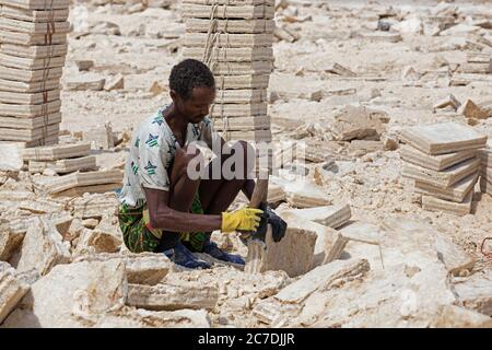 Afar Salzbergmann in Salzbergwerk in Salz flachen Hackklötze / Fliesen / Gandel für Kamelkarawane, Danakil Depression, Äthiopien, Afrika Stockfoto