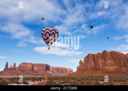 USA, Arizona, Monumnet Valley, Heißluftballons während des Balloon Festivals fliegen über Kamel Butte im Navajo Tribal Park. Die drei Schwestern sind links. Stockfoto