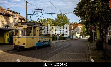 Breite Aufnahme einer gelben Straße, die in der Nähe von Häusern fährt Und trainiert unter blauem Himmel Stockfoto