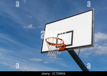 Isolierte Ansicht eines Basketballkorbs und Backboards unter einem ausdrucksstarken blauen Himmel mit Kopierraum Stockfoto