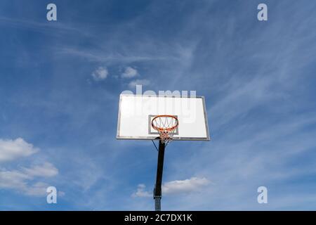 Isolierte Ansicht eines Basketballkorbs und Backboards unter einem ausdrucksstarken blauen Himmel mit Kopierraum Stockfoto