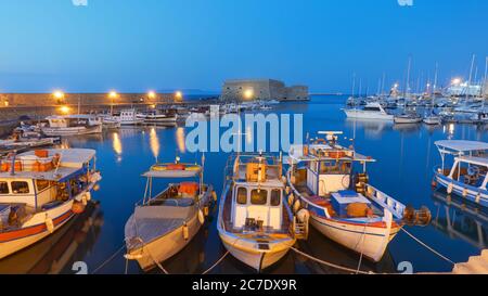 Fischerboote im Hafen in der Nähe der Festung Koules in Heraklion bei Nacht, Kreta, Griechenland. Griechische Landschaft Stockfoto