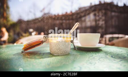 Tasse Kaffee und Dessert mit Chia-Samen in einem Glas auf einem Tisch in einem Café draußen Stockfoto