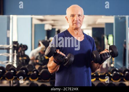 Ein Porträt von kahlen älteren Mann im Turnhalle Training mit Hanteln. Menschen, Gesundheit und Lifestyle-Konzept Stockfoto
