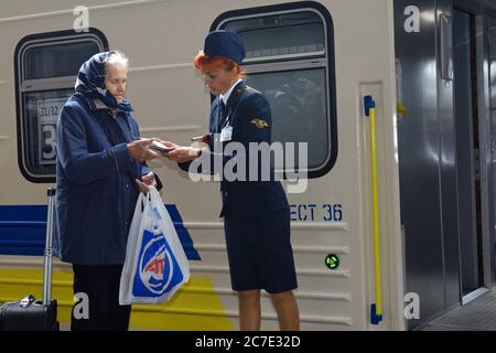 Weibliche Dirigentin prüft Papiere, die vor einer Tür zu einem Wagen stehen Stockfoto