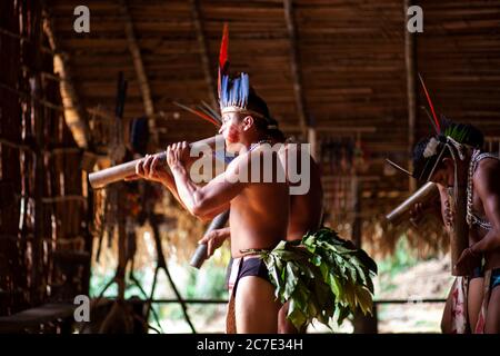 Indigene Männer blasen auf einem traditionellen Instrument Stockfoto