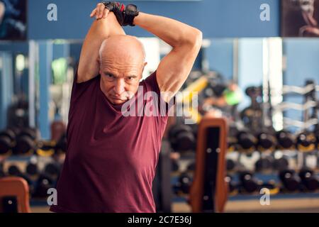 Ein Porträt von kahlen Senior Mann beim Training vor dem Training in der Turnhalle. Menschen, Gesundheit und Lifestyle-Konzept Stockfoto