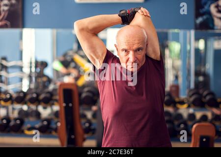 Ein Porträt von kahlen Senior Mann beim Training vor dem Training in der Turnhalle. Menschen, Gesundheit und Lifestyle-Konzept Stockfoto