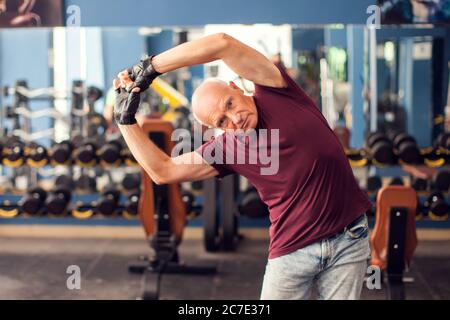 Ein Porträt von kahlen Senior Mann beim Training vor dem Training in der Turnhalle. Menschen, Gesundheit und Lifestyle-Konzept Stockfoto