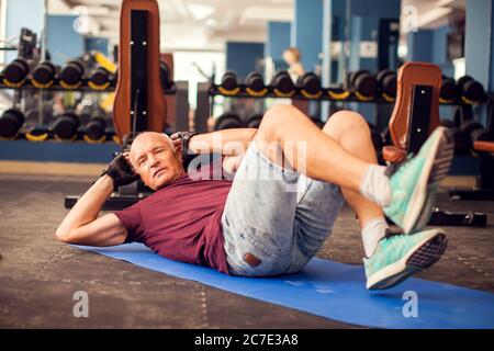 Ein Porträt von kahlen Senior Mann tun abs-Übung in der Turnhalle. Menschen, Gesundheit und Lifestyle-Konzept Stockfoto