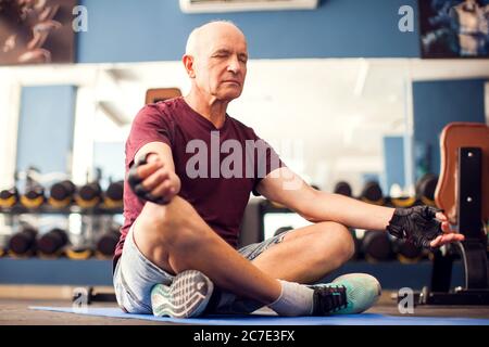 Ein Porträt von kahlen älteren Mann tun Entspannung Übung im Fitnessstudio. Menschen, Gesundheit und Lifestyle-Konzept Stockfoto