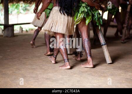 Indigene Amazonas-Männer führen eine traditionelle Stammeszeremonie mit zeremoniellen Stäben durch, tragen gefiederte Kopfbedeckungen und Körperfarbe, um ihre zu feiern Stockfoto