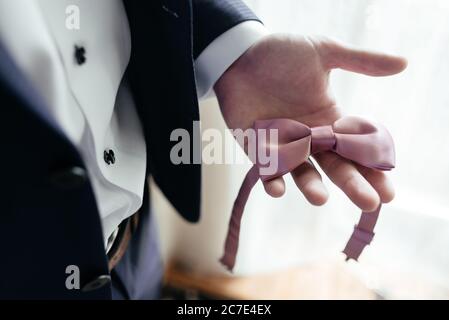 Geschäftsmann hält rosa Fliege in der Hand. Hochzeitsmann Accessoires. Nahaufnahme Stockfoto