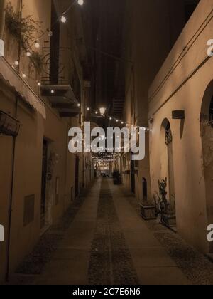 Vertikale Aufnahme einer leeren Gasse in der Mitte von Gebäude bei Nacht Stockfoto