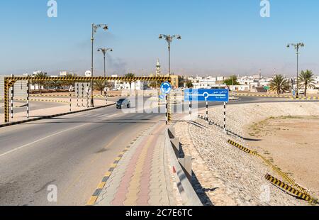 Sur, Oman - 15. Februar 2020: Die Straße in Sur City mit Straßenschild zeigt das Stadtzentrum und den Strand, Sultanat von Oman eingeben. Stockfoto