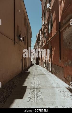 Vertikale Aufnahme einer leeren Gasse in der Mitte von Gebäude unter blauem Himmel am Tag Stockfoto