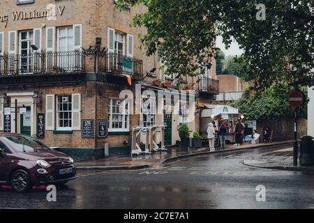 London, Großbritannien - 02. Juli 2020: Menschen, die unter dem Regen Schlange stehen für La Creperie de Hampstead in Hampstead, einem wohlhabenden Gebiet, das von Akademikern, Künstlern und Künstlern bevorzugt wird Stockfoto