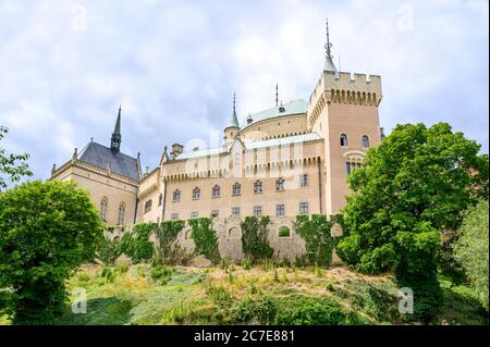 Blick auf das neugotische Bojnice Schloss mit kleiner Befestigungsmauer aus dem Schlosspark (Bojnice, Slowakei) Stockfoto