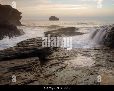 Dämmerung am Trebarwith Strand Beach, wenn die Flut kommt heftig über die Felsen krachend. Stockfoto