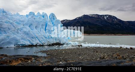 Perito Moreno Gletscher mit Mini Eisbergen im Wasser ringsum und Bergen im Hintergrund Stockfoto