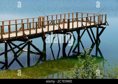 Fischfang auf hölzernen Pier am See. Stockfoto
