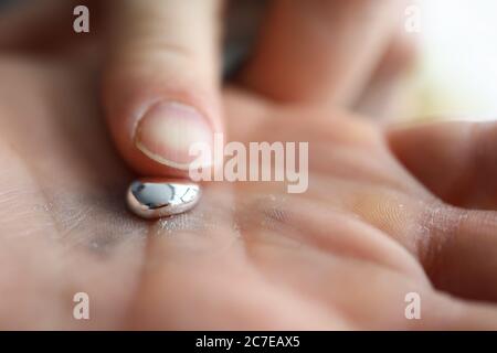 Männliche Hand hält Stück flüssiges Gallium Stockfoto