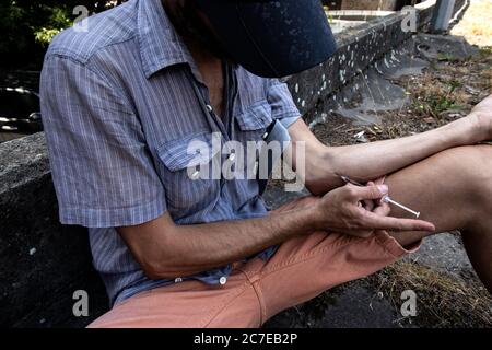 Hände eines Drogenabhängigen mit einer Spritze voll Betäubungsmittel, Heroin oder Kokain in die Armvenen. Drogenabhängigkeit und Entzugserscheinung. Stockfoto