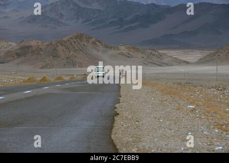 Ein Bus auf dem Weg von Olgii, Westmongolei, fährt auf dem Pferderücken an einem ethnischen kasachischen Nomaden vorbei. Stockfoto