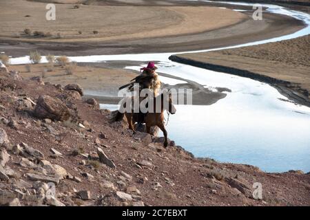 Einem kasachischen Nomaden zu Pferd Jagd mit seinem goldenen Adler in den Altai Gebirge der westlichen Mongolei. Stockfoto