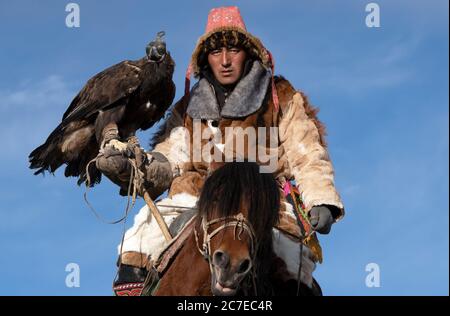 Einem kasachischen Nomaden zu Pferd Jagd mit seinem goldenen Adler in den Altai Gebirge der westlichen Mongolei. Stockfoto