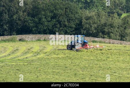 Ein Traktor, der eine Zettmaschine auf einer Yorkshire Farm in England zieht. Stockfoto